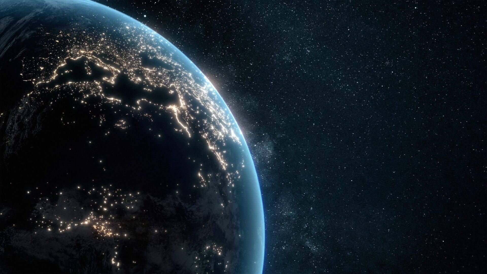 View of Earth from space showing city lights at night and starry background.